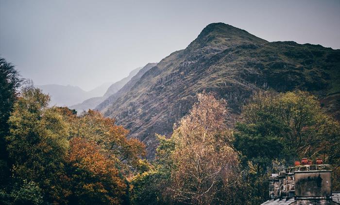 The picture is dominated by the large mountains of Snowdonia. In the foreground, you can see the chimneys of the cottages on site at the museum
